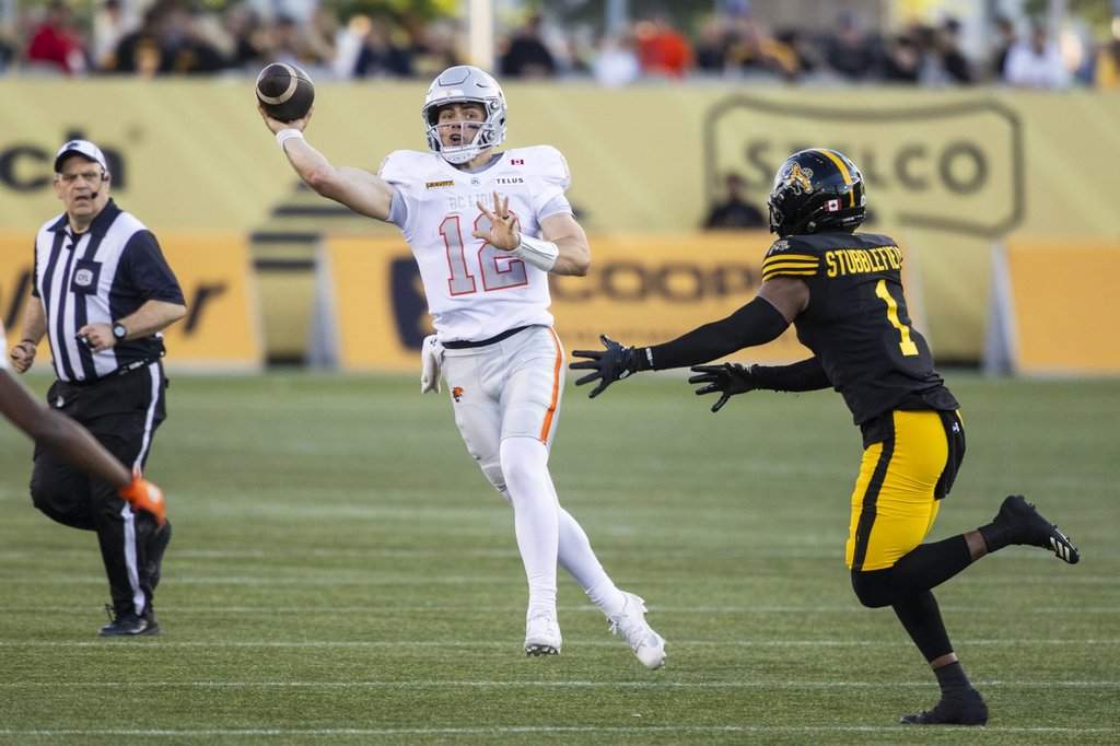 B.C. Lions quarterback Nathan Rourke (12) throws the ball past Hamilton Tiger-Cats' Reggie Stubblefield (1) during first-half CFL football action in Hamilton on Friday, June 19, 2026. THE CANADIAN PRESS/Nick Iwanyshyn.