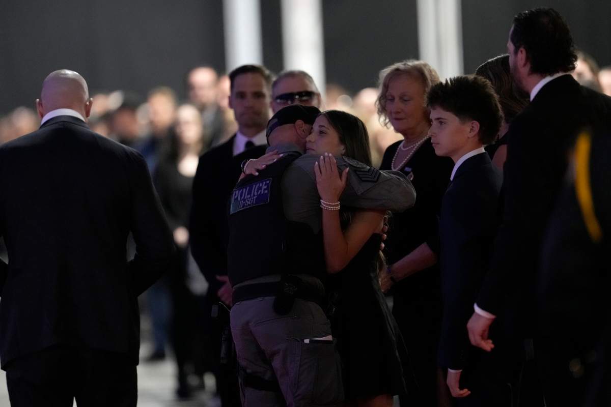 Sergeant Kent LeFort with ETF – Team 2 hugs fallen Toronto Police Constable Marc Pinizzotto’s daughter Daniella, at Pinizzotto’s funeral in Toronto, on Wednesday, June 24, 2026.
