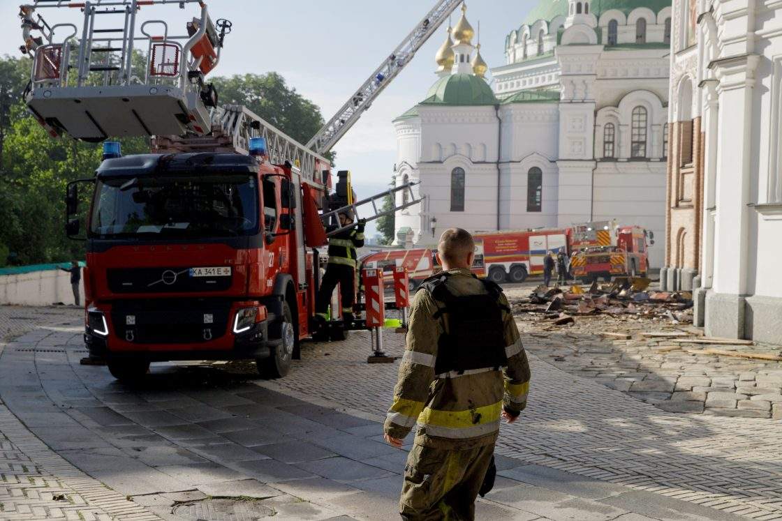 A firefighter stands in front of firefighting vehicles behind the Dormition Cathedral at the Kyiv Pechersk Lavra, where the roof caught fire during a massive Russian combined attack, Kyiv, Ukraine, June 15, 2026. 