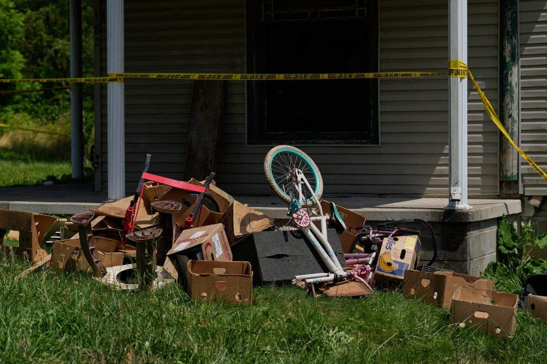 Police tape and debris are seen at a home where authorities say they removed 16 children and arrested four adults in Hamden, Ohio, July 1, 2026.