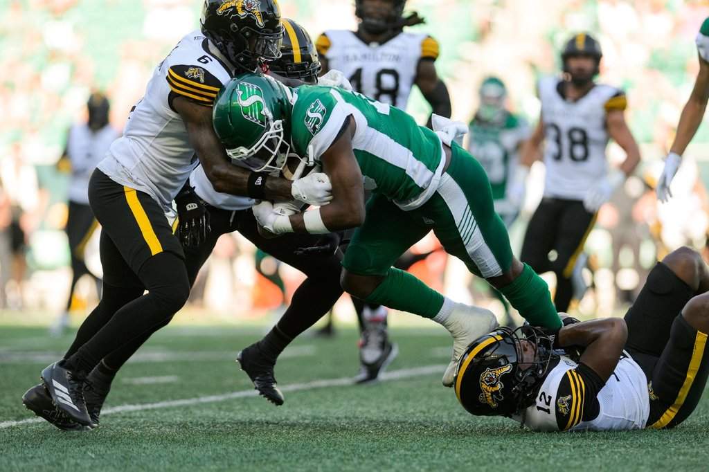 Saskatchewan Roughriders Samuel Emilus (19) fights for a first down against Hamilton Tiger-Cats' Zamari Walton (6) during first half CFL football action in Regina, Sunday, July 12, 2026. THE CANADIAN PRESS/Derek Elvin.