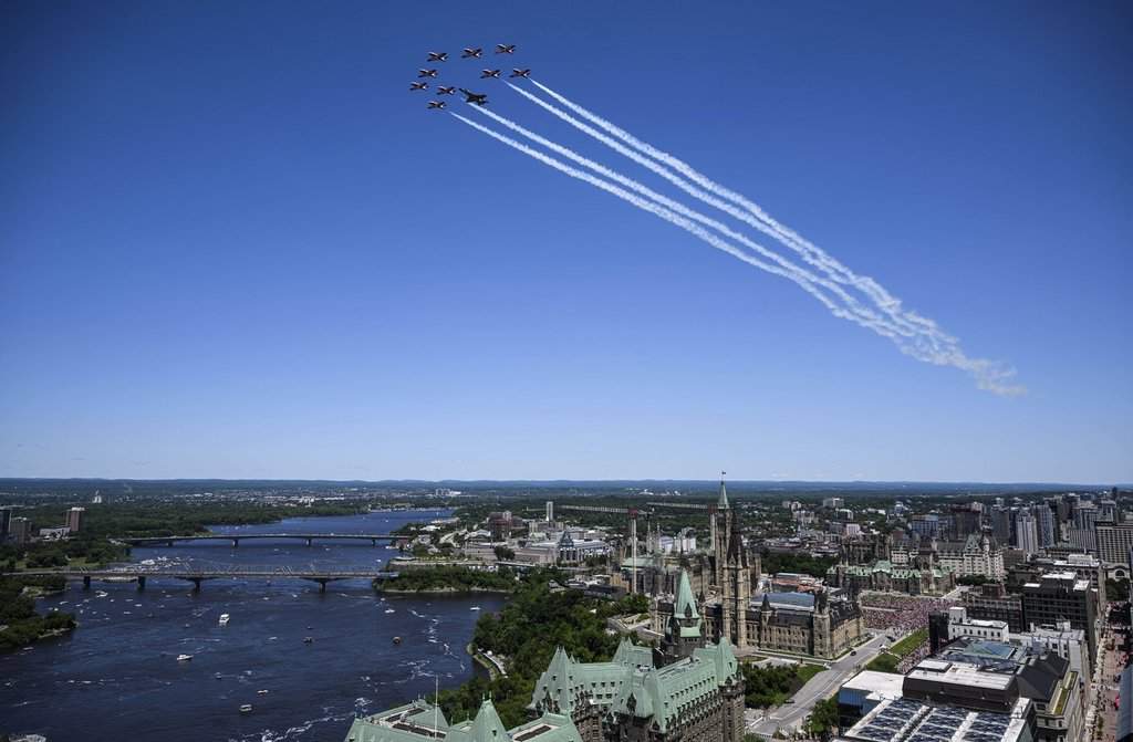 Royal Canadian Air Force Snowbirds and a CF-18 Hornet fly over Parliament Hill during a 2024 flypast celebrating the RCAF centennial on Canada Day in Ottawa.