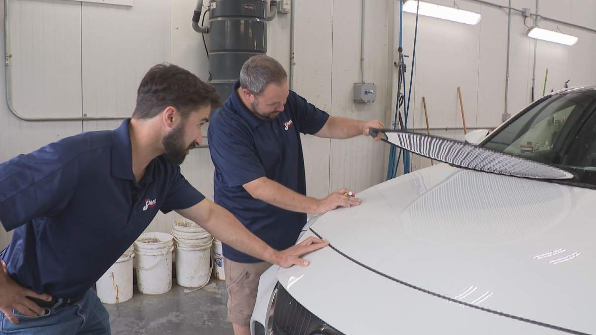 George Semchuk and Tim Prokipchuk assess hail damage on a vehicle at J Max Collision & Glass. 