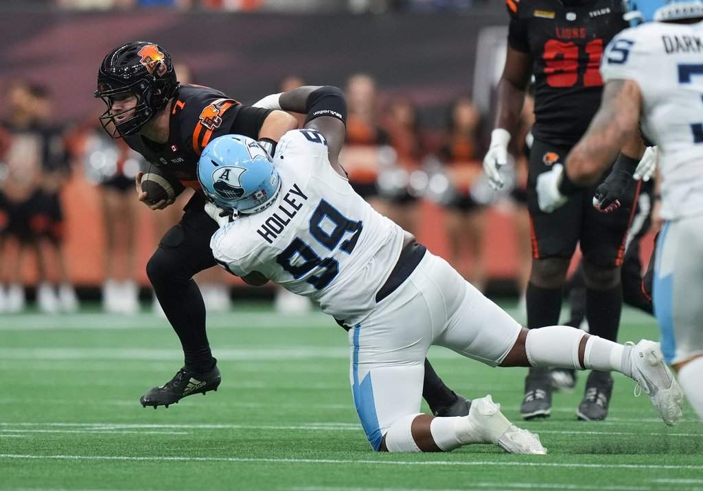 B.C. Lions quarterback Chase Brice (7) is tackled by Toronto Argonauts' Ralph Holley (99) as he carries the ball during the first half of a CFL football game, in Vancouver, on Saturday, July 25, 2025. THE CANADIAN PRESS/Darryl Dyck.