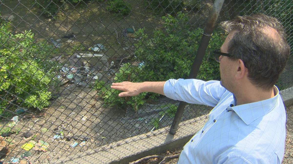 Marvin Sharp points to the garbage left on his property by residents of a nearby encampment.