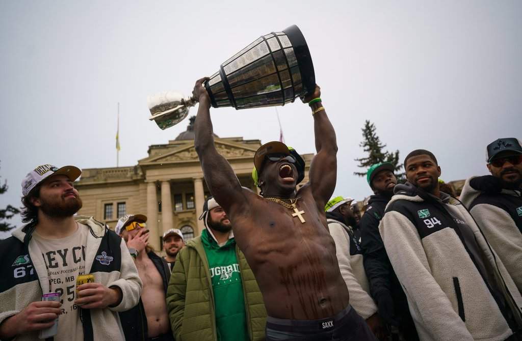 Saskatchewan Roughriders receiver Ajou Ajou lifts the Grey Cup during a Grey Cup championship parade in Regina, Tuesday, Nov. 18, 2025. The Saskatchewan Roughriders defeated the Montreal Alouettes on Sunday to become Grey Cup champion for the fifth time in team’s history. THE CANADIAN PRESS/Heywood Yu.