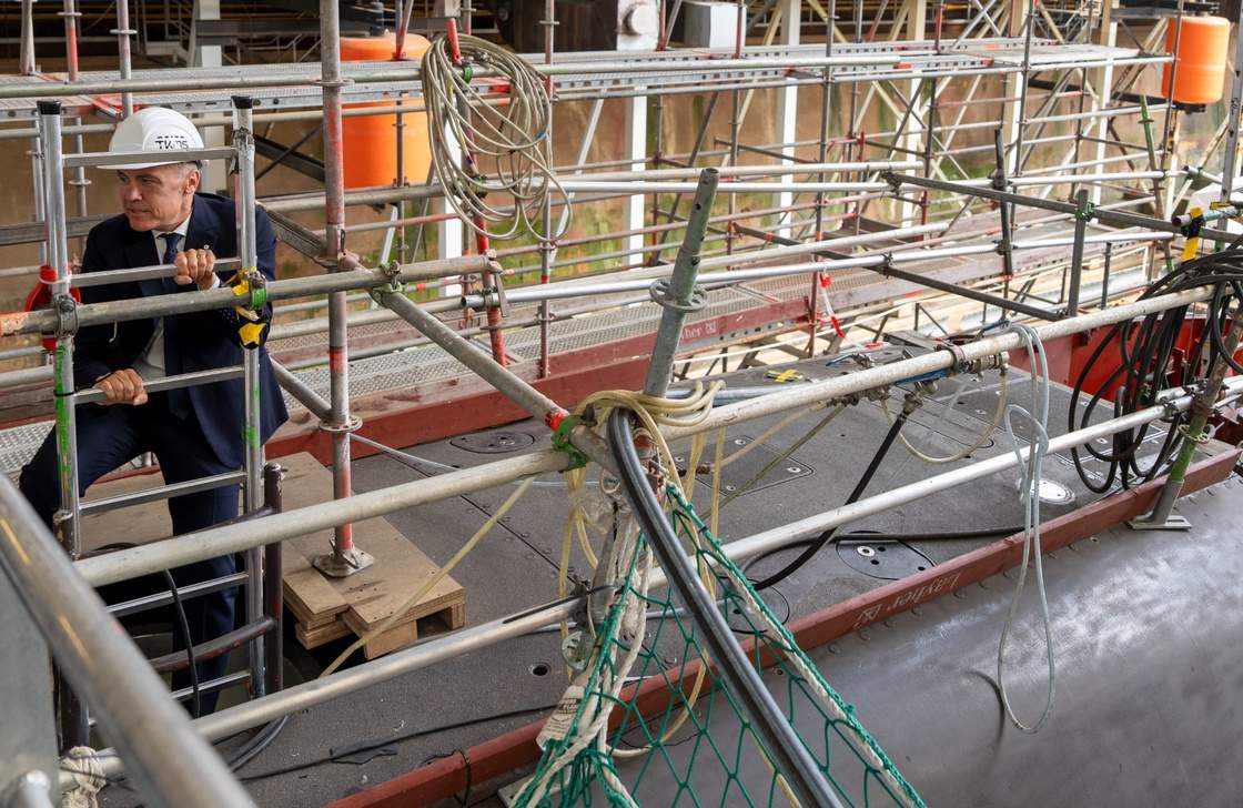 Prime Minister Mark Carney climbs out of a 212A class submarine under maintenance as he tours ThyssenKrupp Marine Systems (TKMS), a submarine building facility in Kiel, Germany, on Tuesday, Aug. 26, 2025. THE CANADIAN PRESS/Christinne Muschi
