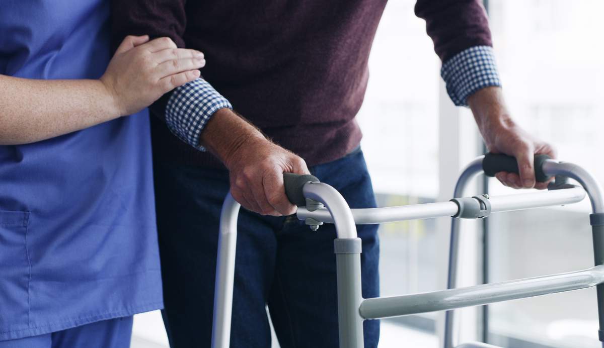 A nurse helps a patient with a walker. Lumi Nola/Getty Images