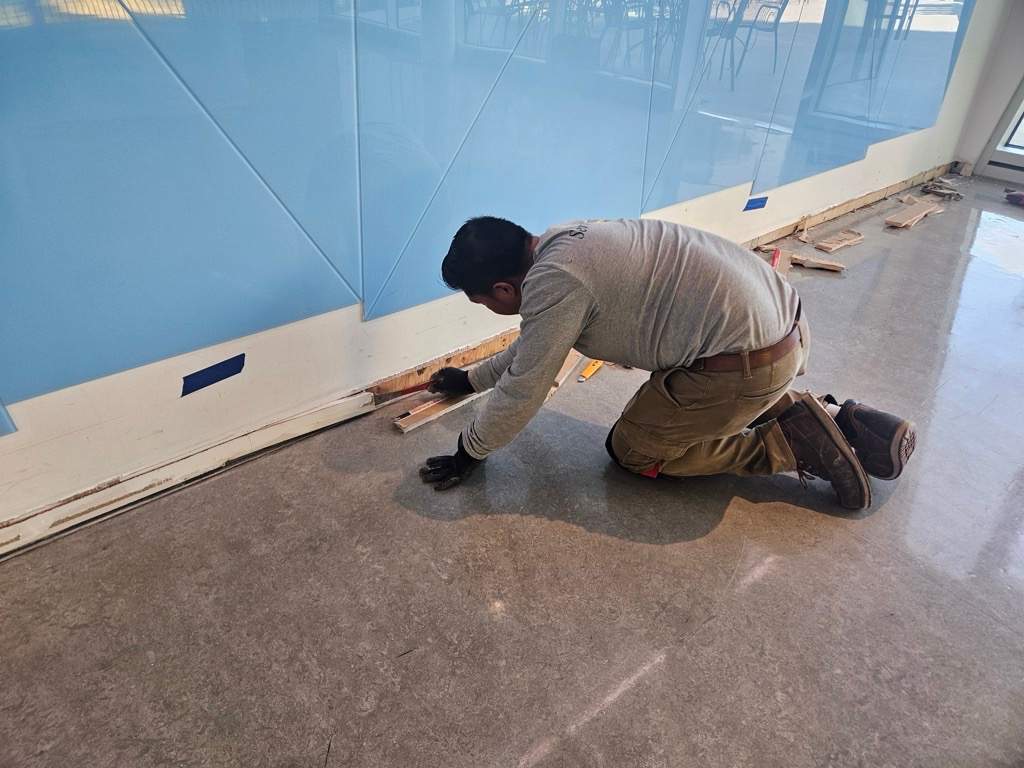 A worker removing a baseboard at the TELUS World of Science.