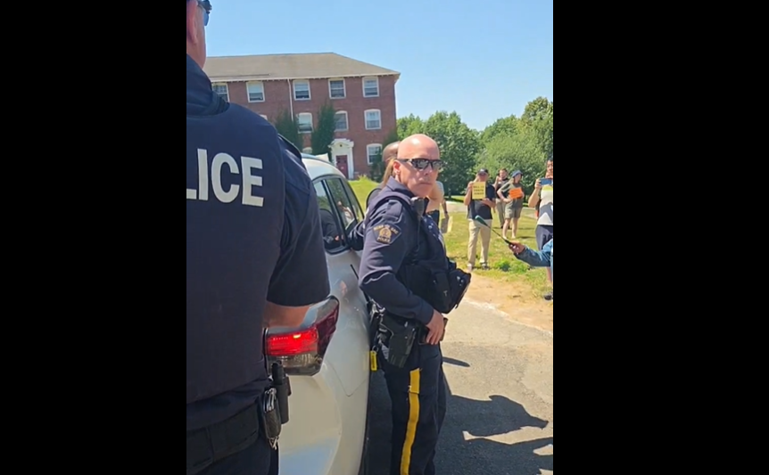 Nova Scotia Premier Tim Houston had to be escorted by RCMP away from a group of protesters in Wolfville, N.S. on July 15, 2026.