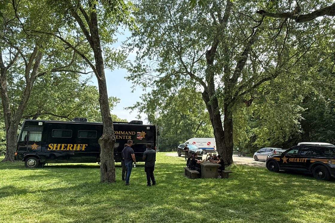 Officials stand at a staging area after an operation to recover multiple people who died while trying to save someone from the Scioto River in the Columbus suburb of Powell, Ohio, Monday, July 20, 2026.