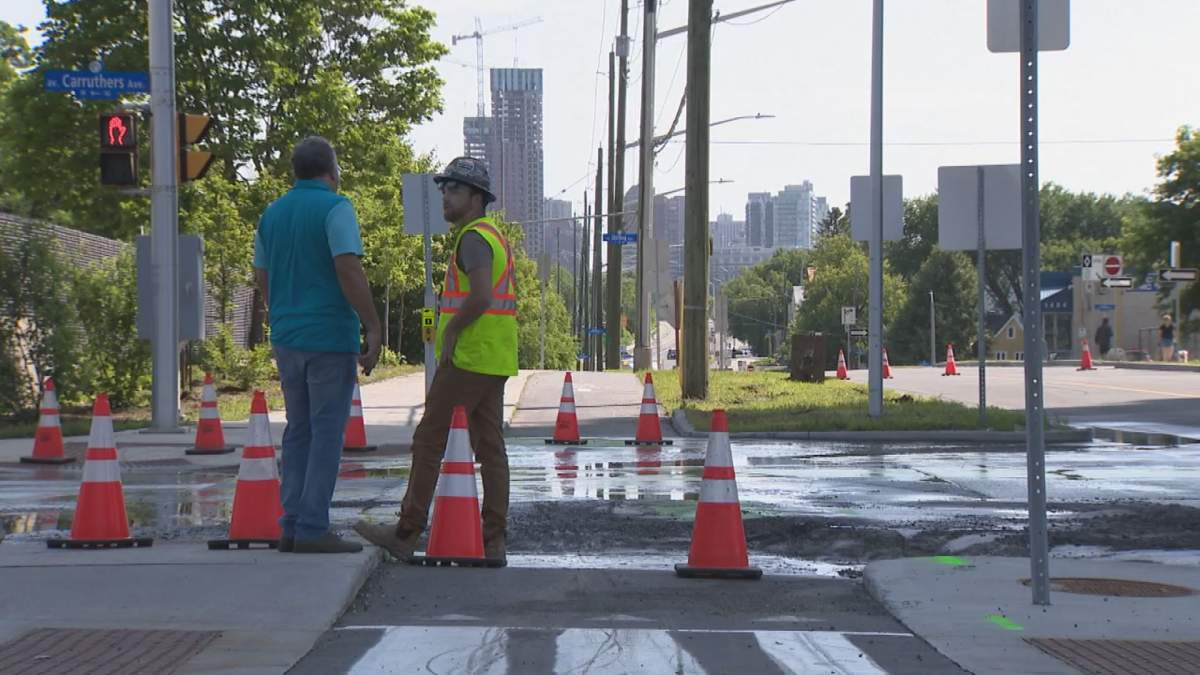 City workers stand on a road in Ottawa on July 2 as work is done following a severe storm in the city July 1.
