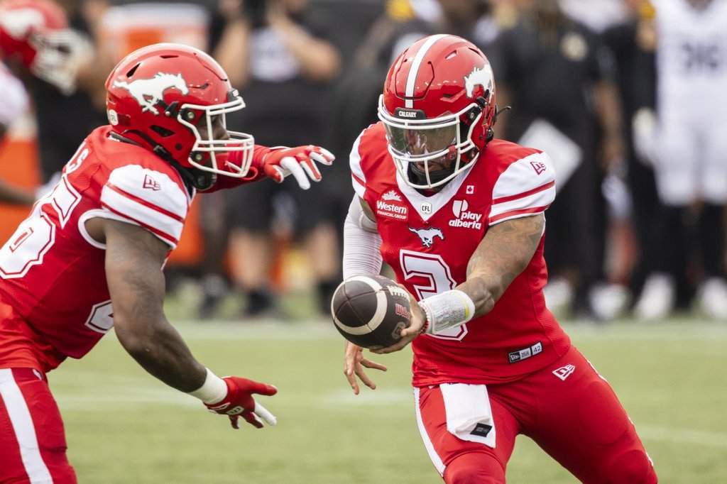 Calgary Stampeders quarterback Vernon Adams Jr. (3) hands the ball off to teammate Dedrick Mills (26) during first half CFL football action against the Hamilton Tiger-Cats, in Hamilton, Saturday, Aug. 1, 2026. THE CANADIAN PRESS/Nick Iwanyshyn.