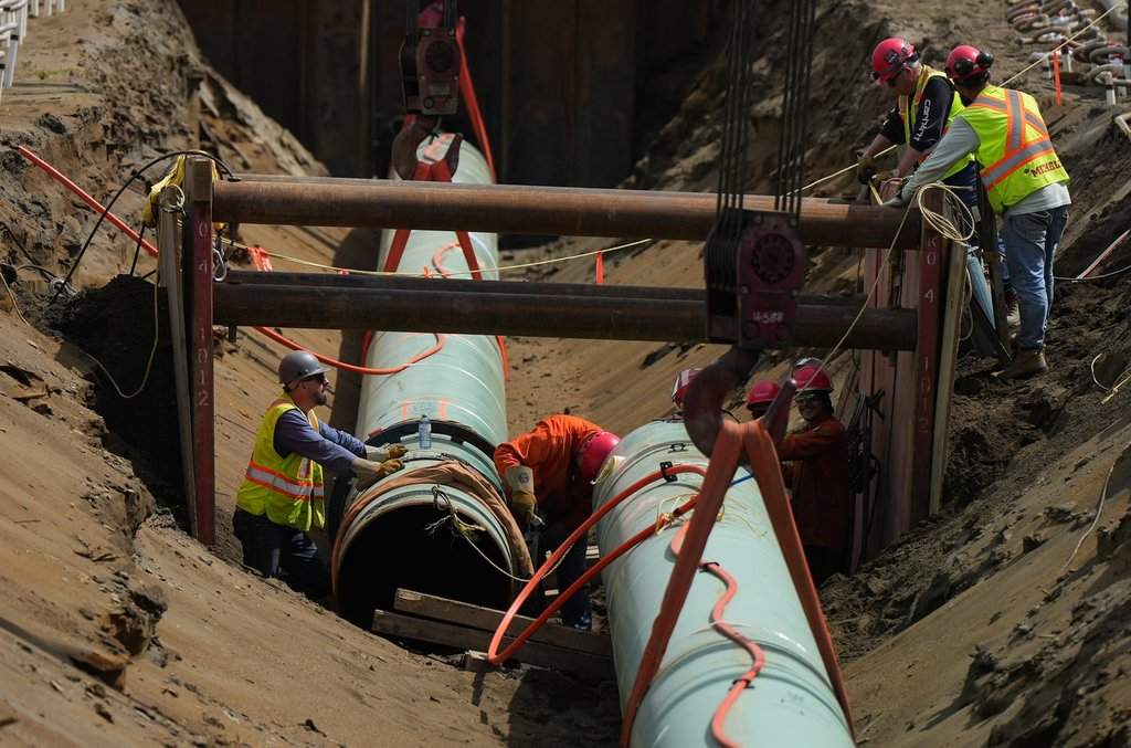 FILE: Workers place pipe during construction of the Trans Mountain pipeline expansion on farmland, in Abbotsford, B.C., on Wednesday, May 3, 2023. 