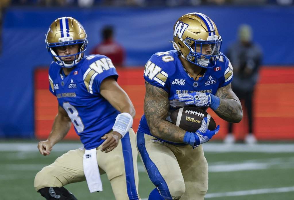 Winnipeg Blue Bombers quarterback Zach Collaros (8) hands off to Brady Oliveira (20) against the Montreal Alouettes during second half CFL football action in Winnipeg on Friday, August 28, 2026. THE CANADIAN PRESS/John Woods.