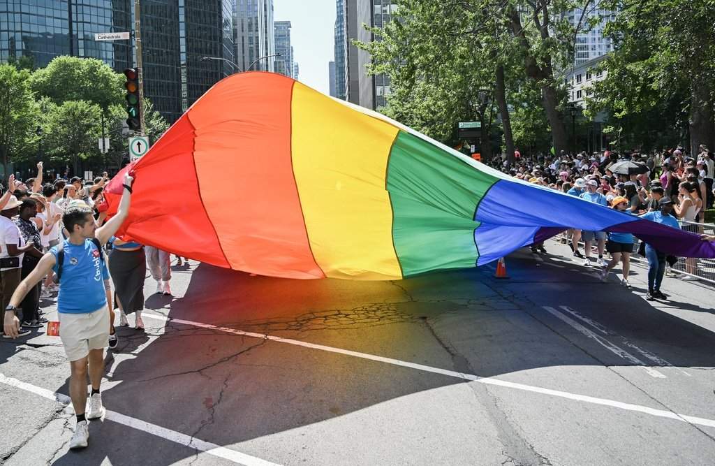 Participants pull a rainbow flag along a street during the Pride parade in Montreal, Sunday, Aug. 10, 2025. 