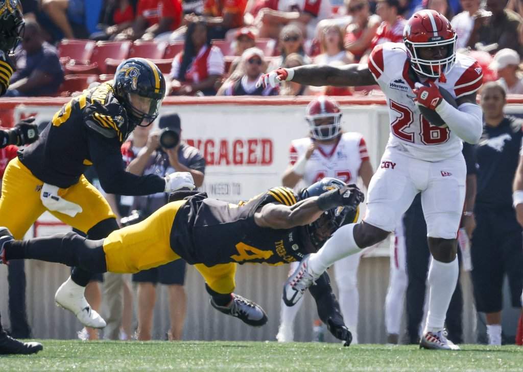 Hamilton Tiger-Cats' Wynton McManis, centre, dives for Calgary Stampeders' Dedrick Mills during first half CFL football action in Calgary, Saturday, Aug. 29, 2026. THE CANADIAN PRESS/Jeff McIntosh.