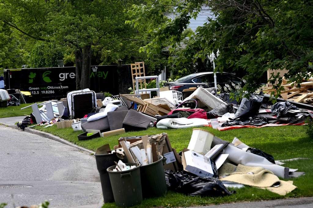 Belongings damaged after a storm on Canada Day flooded basements are seen on lawns to await disposal, in the Qualicum – Graham Park neighbourhood of Ottawa, on Tuesday, July 7, 2026. THE CANADIAN PRESS/Justin Tang.