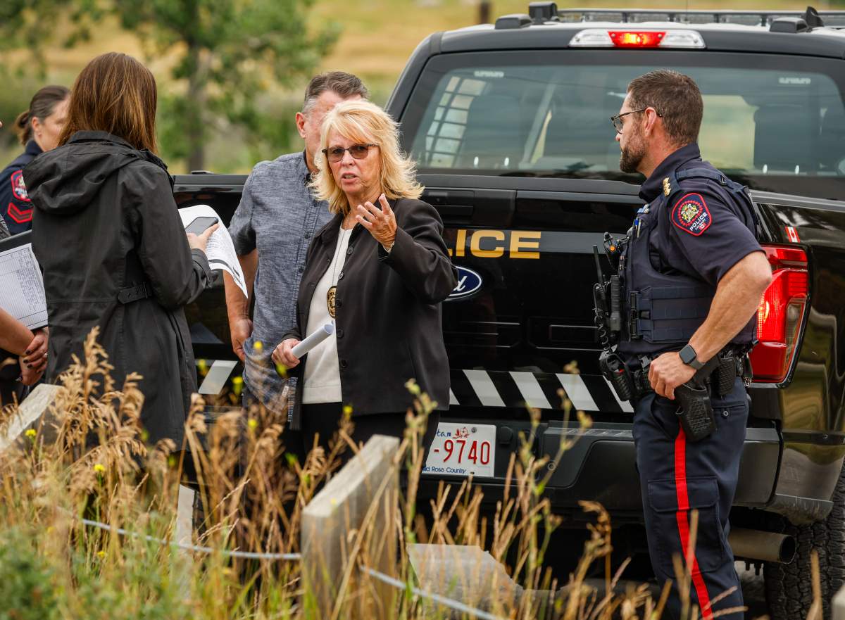 Calgary Police Service Chief Katie McLellan, centre, speaks with other officers at the scene of an officer-involved shooting that took place near Edworthy Park in Calgary, Monday, Aug. 10, 2026.