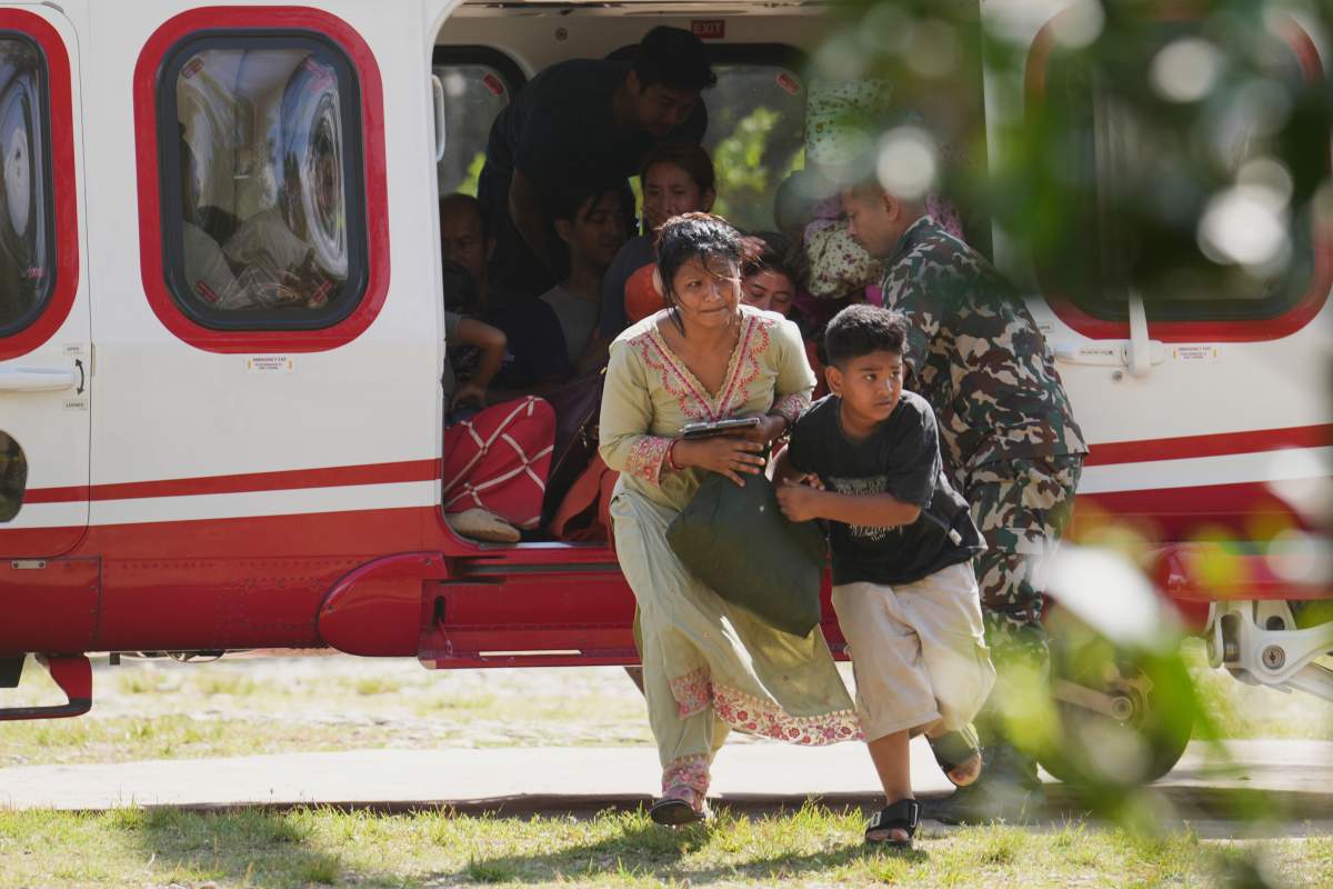 Army soldiers help a family disembark from a helicopter after they are rescued from an area affected by flash flooding in Nepal’s Nuwakot district, Friday, Aug. 28, 2026. (AP Photo/Rajesh Kumar Singh)