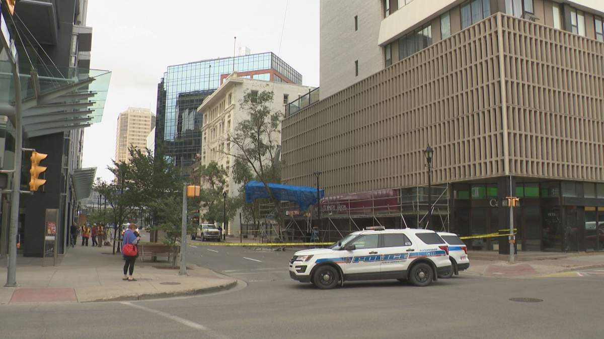 A wide shot of Regina's downtown Hamilton Street. A police car blocks its entry, and collapsed scaffolding lies in a tree outside a building behind the car.
