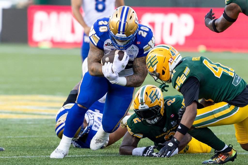 Winnipeg Blue Bombers' Brady Oliveira (20) rushes with the ball against the Edmonton Elks defence during first half CFL football action in Edmonton on Friday, August 21, 2026. THE CANADIAN PRESS/Timothy Matwey.