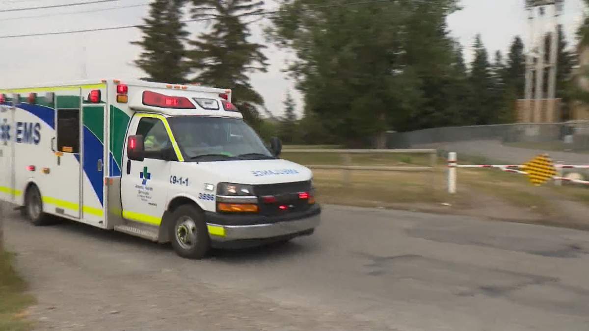 A ambulance with lights and siren activated leaves an area near Edworthy Park in Calgary's southwest where an officer was shot during a traffic stop on Monday.