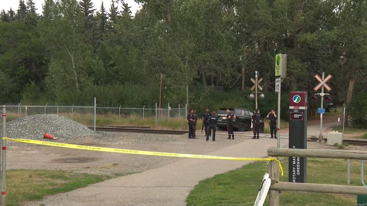 A group of heavily armed police officers are shown blocking off one of the entrances to Edworthy Park, in Calgary's southwest, as they search the area for the suspect who shot an officer during a nearby traffic stop.
