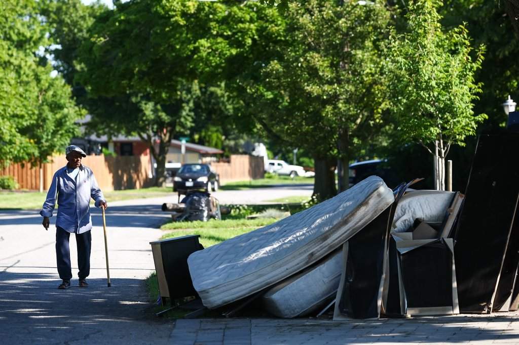 A man walks by a pile of belongings cleared out from a flooded house in St. Catharines' north end neighbourhood following flash floods from heavy rainfall in the area, Wednesday, Aug. 5, 2026. 