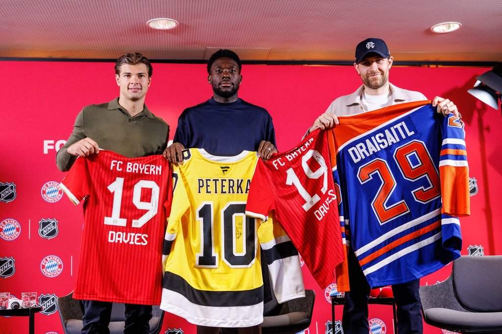 Boston Bruins’ John-Jason Peterka, from left, FC Bayern Munich’s Alphonso Davies, and Edmonton Oilers Leon Draisaitl, pose with jerseys during a joint press conference by FC Bayern Munich and the National Hockey League, Thursday, Aug. 20, 2026, in Munich.