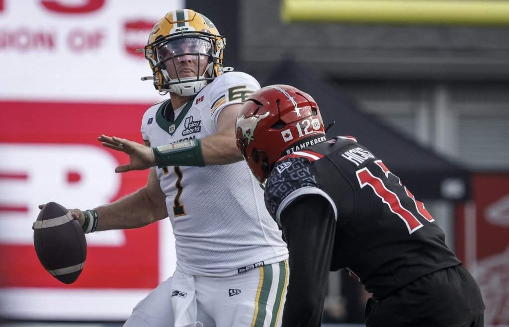 Edmonton Elks quarterback Cody Fajardo, left, looks for a receiver as Calgary Stampeders' Clarence Hicks closes in during second half CFL football action in Calgary, Alta., Monday, Sept. 1, 2025. THE CANADIAN PRESS/Jeff McIntosh.