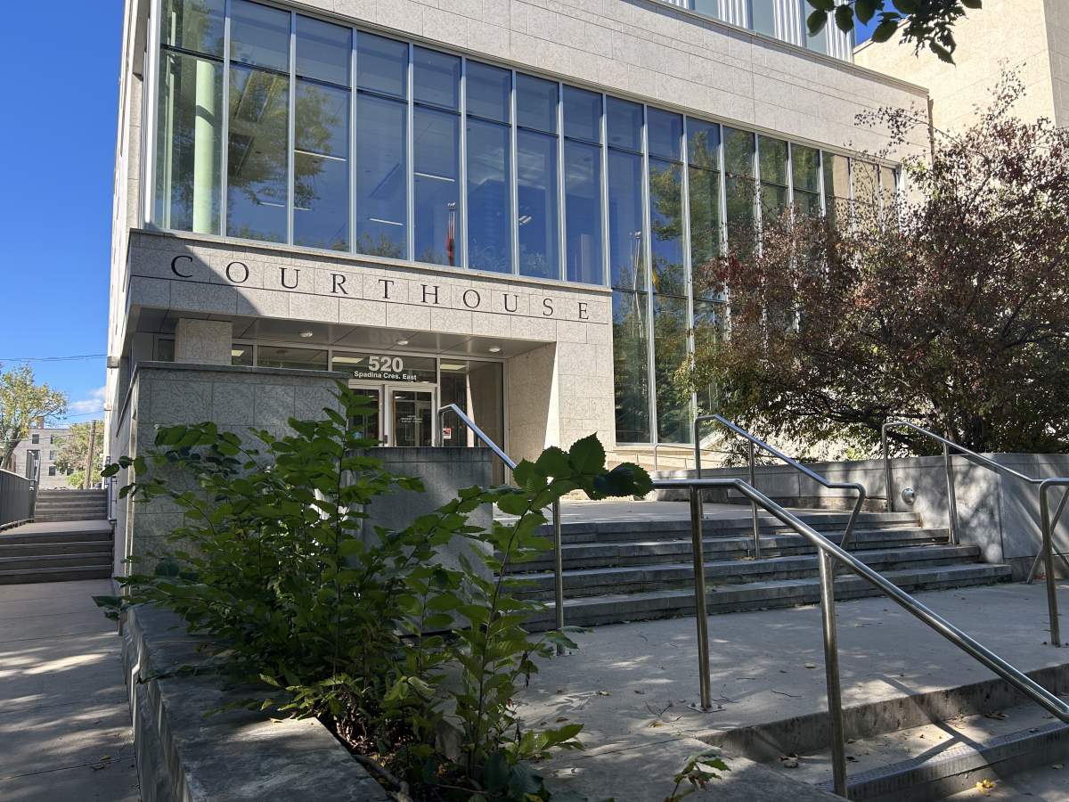 A white building with large glass window panes sits in front of a blue sky with the words "Court House" sprawled across the front in large black lettering.