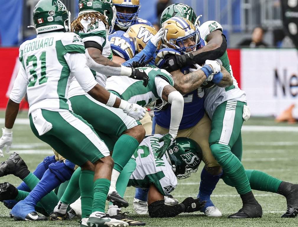 Winnipeg Blue Bombers' Brady Oliveira (20) gets stopped by Saskatchewan Roughriders as he runs for the first down during first half CFL action in Winnipeg, Saturday, Sept. 12, 2026. THE CANADIAN PRESS/John Woods.