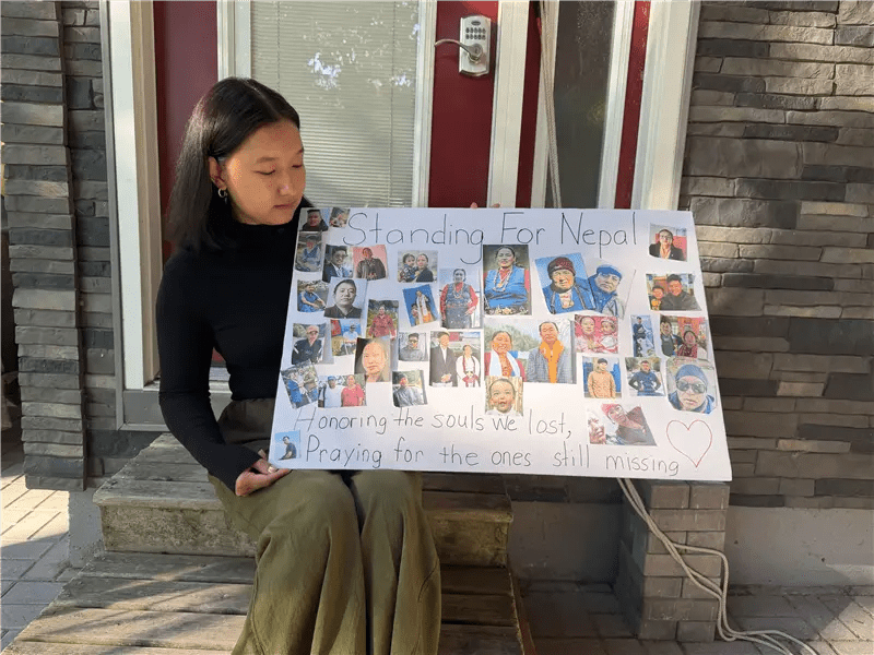 Ang Faulkner holds up photos of her missing relatives and neighbours. She says the poster represents less than five per cent of the people her family has lost.
