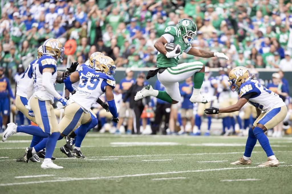 Saskatchewan Roughriders running back Quali Conley (24) leaps in the air as the Winnipeg Blue Bombers defence closes in during first half CFL action in Regina on Sunday, Sep. 6, 2026. THE CANADIAN PRESS/Kayle Neis.