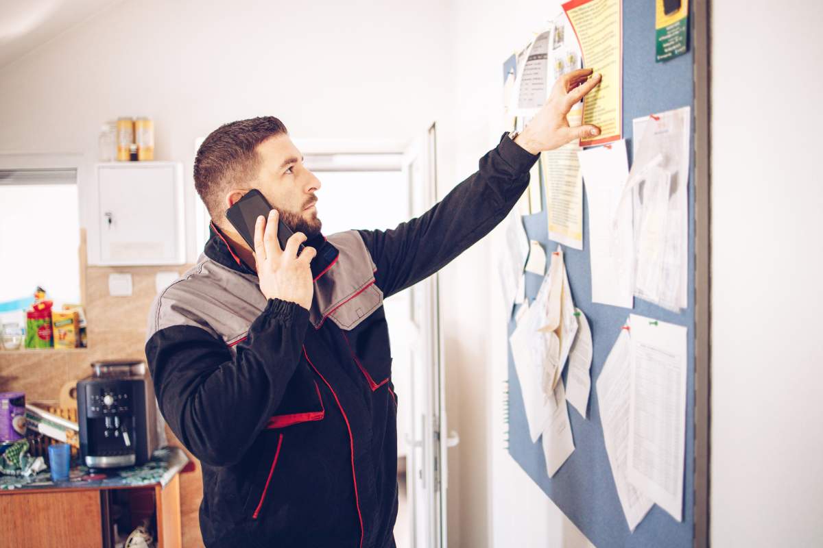 The car service technician check to do list and talk with client by phone.