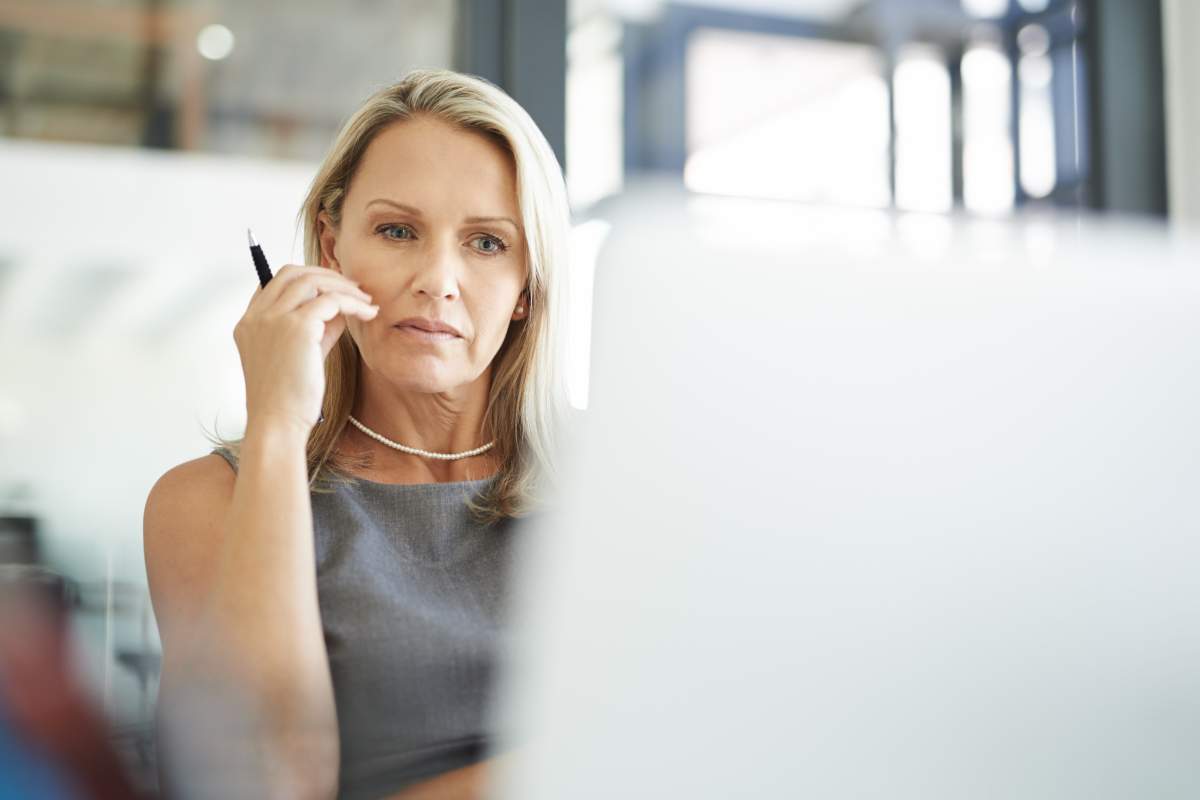 Shot of a mature businesswoman using a laptop in a modern office and looking thoughtful.