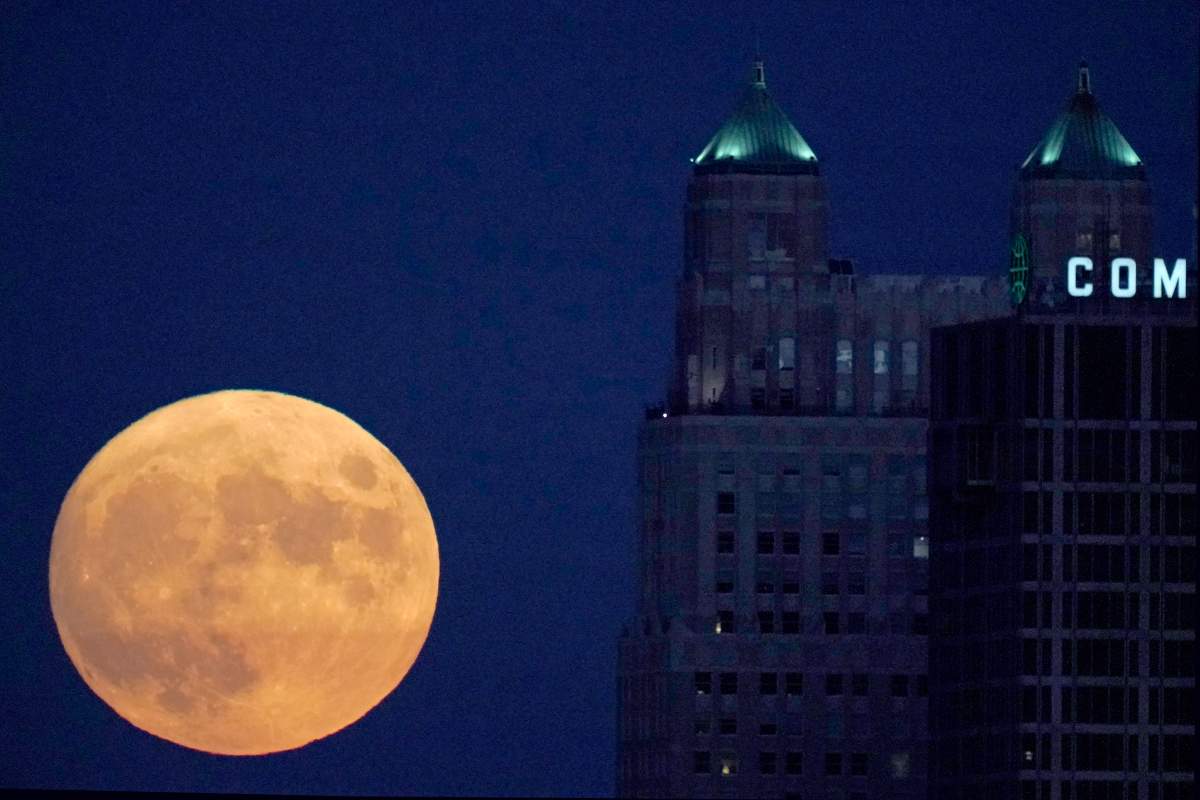 The full harvest moon rises behind downtown buildings, Friday, Sept. 9, 2022, in Kansas City, Mo. (AP Photo/Charlie Riedel)