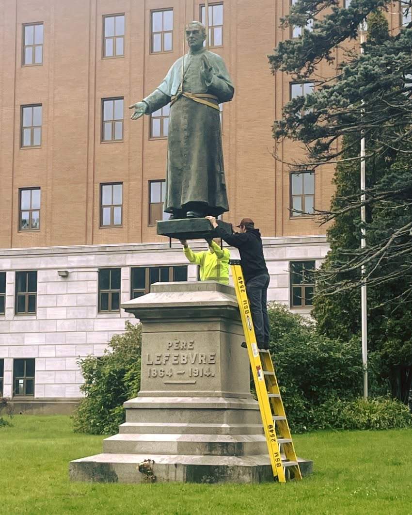 The statue of Père Camille Lefebrve is placed back on its base in Memramcook, N.B. after it was pushed off by vandals in August 2026.