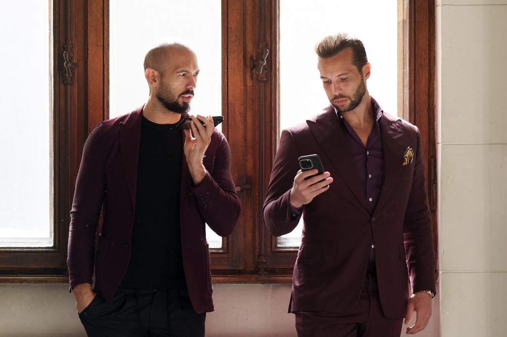 Andrew Tate, left, and his brother Tristan, right, wait at the Court of Appeals building in Bucharest, Romania, Tuesday, Oct. 15, 2024.