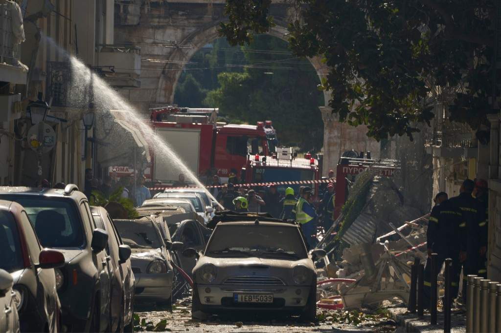 Firefighters work at the scene following a powerful blast that caused a building to collapse and injured at least two people in Athens' Plaka district, with the ancient Hadrian's Arch in the background, Friday, Sept. 25, 2026.