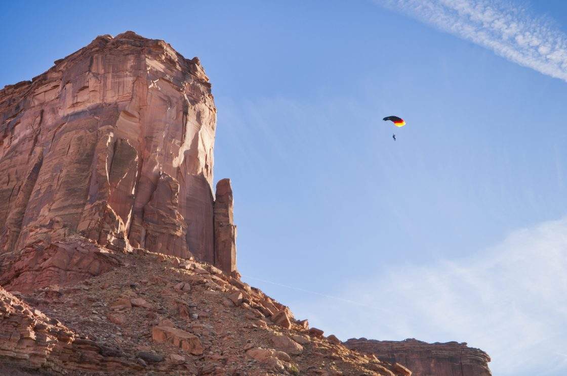 A BASE jumper parachutes through a Utah canyon.