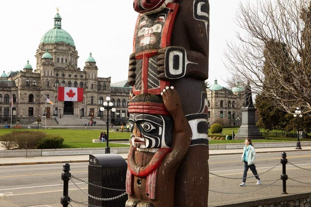 A gigantic Canadian flag hangs over the ceremonial entrance at the legislature as people walk about in Victoria, Friday, March 7, 2025. THE CANADIAN PRESS/Chad Hipolito.