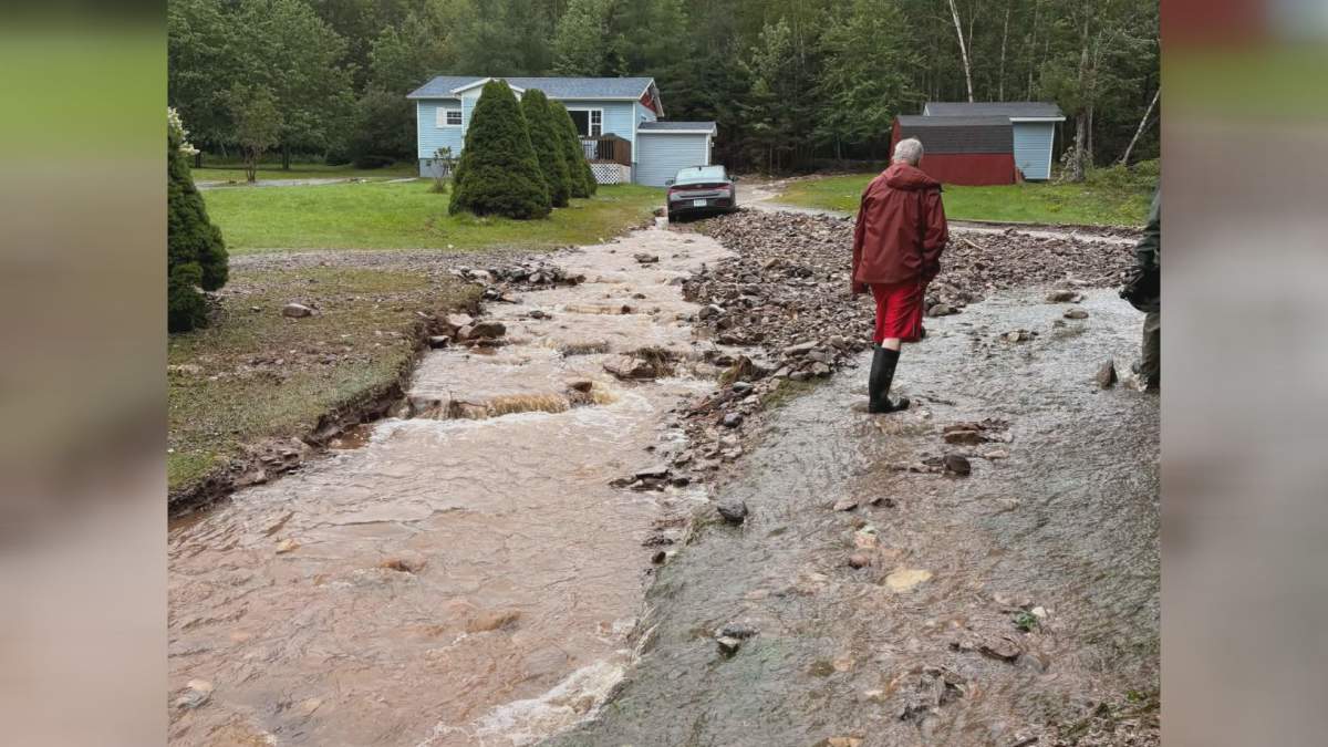 A woman walks by a washed out road in River Bourgeois, N.S. on Sept. 5