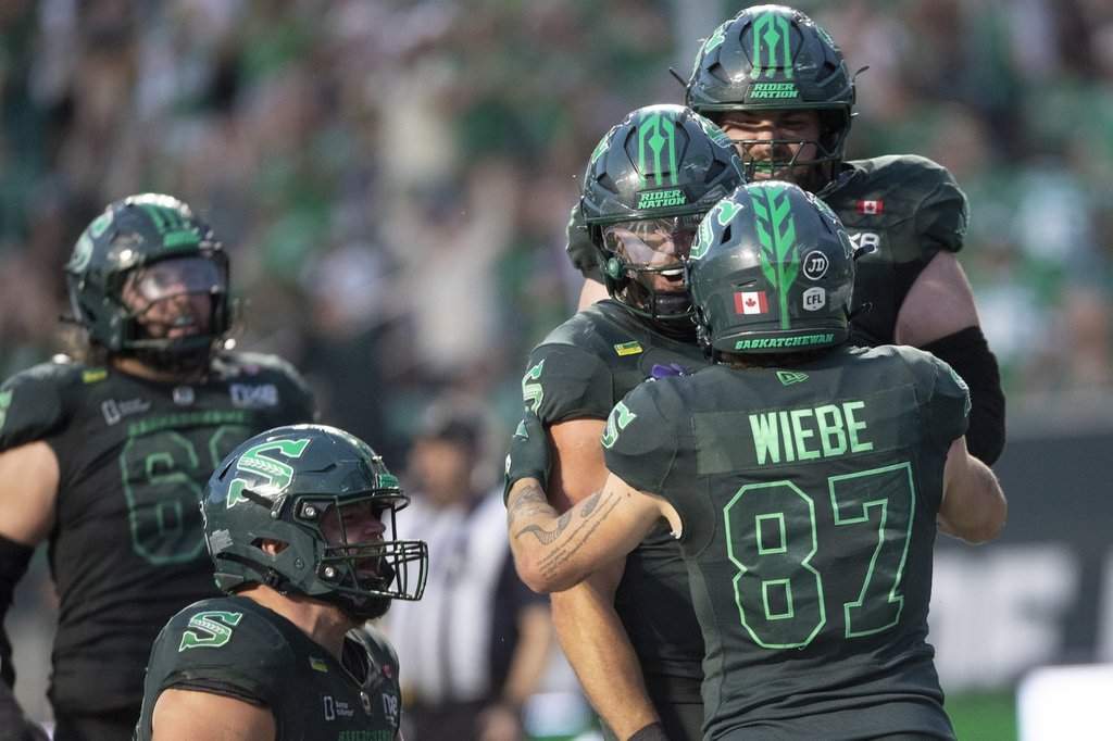 Saskatchewan Roughriders quarterback Tommy Stevens (centre) is embraced by Daniel Wiebe (87) after scoring a touchdown against the Toronto Argonauts during second half CFL football action in Regina on Saturday, Aug. 29, 2026. THE CANADIAN PRESS/Kayle Neis.