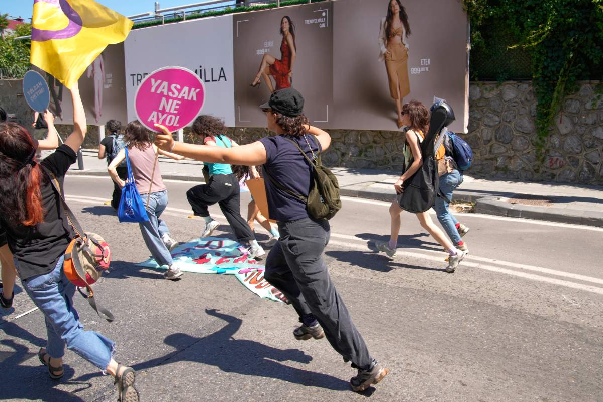 People run from the police during a march in support of transgender people and their rights during the LGBTQ Pride week, in Istanbul, Turkey, Sunday, June 21, 2026. The placard reads in colloquial Turkish: "What's forbidden. Come on!". 