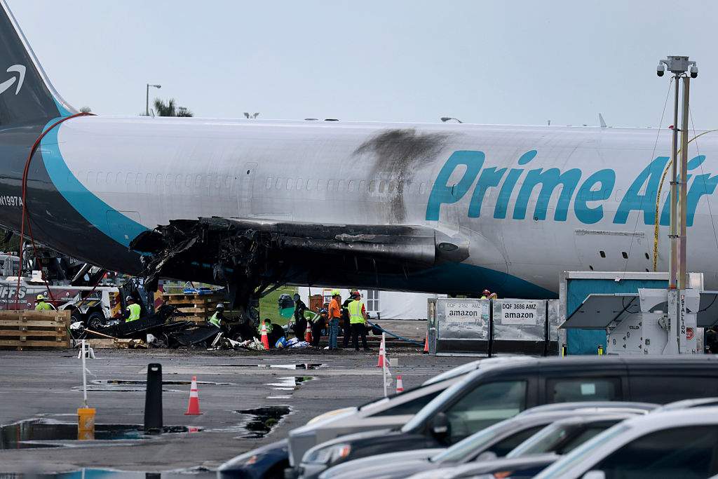 Workers prepare to move the Amazon cargo plane that crashed at Miami International Airport on September 14, 2026 in Miami, Florida. Amazon announced it has decided to suspend its operations with 21 Air after the carrier's plane overshot the runway in Miami, killing five people on September 6th.  