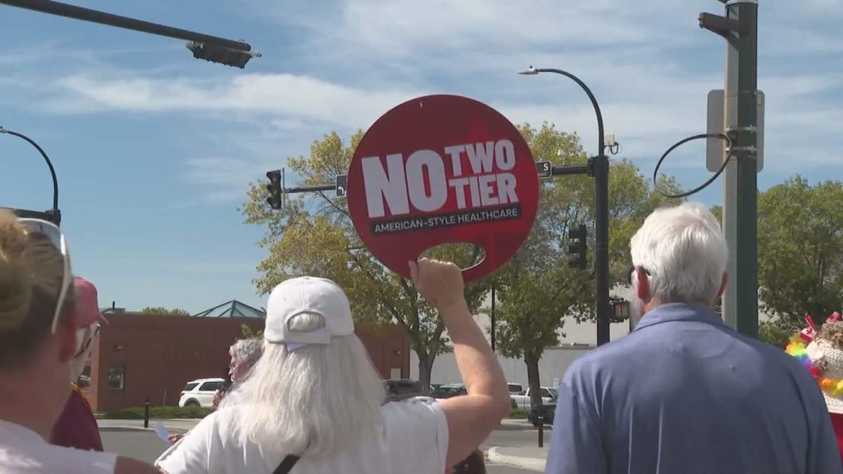 Protestor holding a sign that reads "no two-tier."