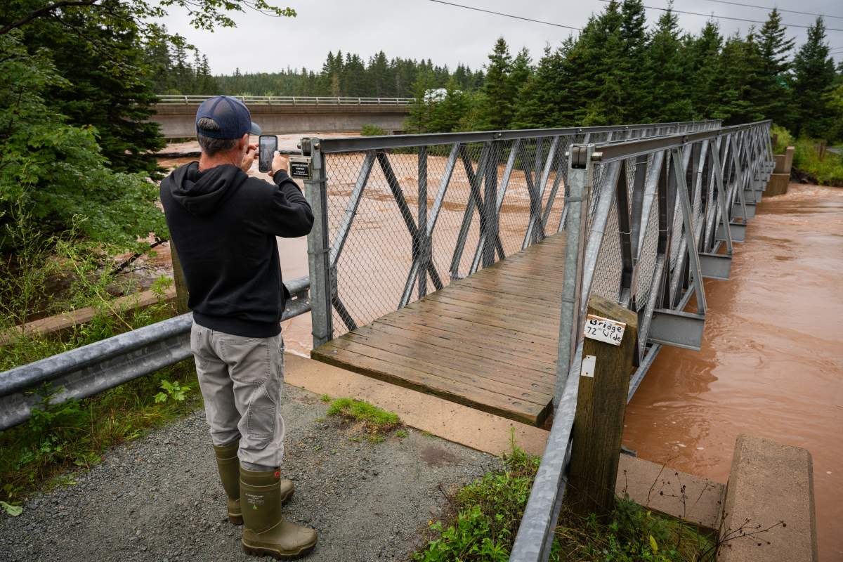 John Burke of River Bourgeois takes photos from an ATV bridge over the flooded River Tillard, in Richmond County, Cape Breton, N.S., Saturday, Sept. 5, 2026. n