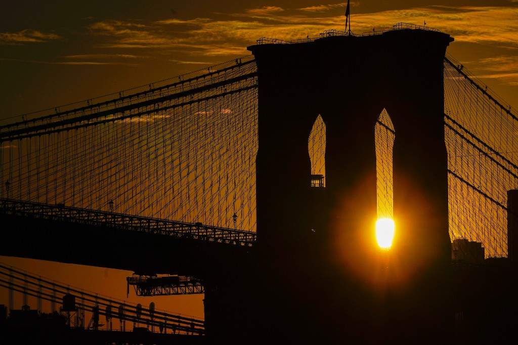 The sun rises behind the Brooklyn Bridge on Oct. 11, 2023, in New York.